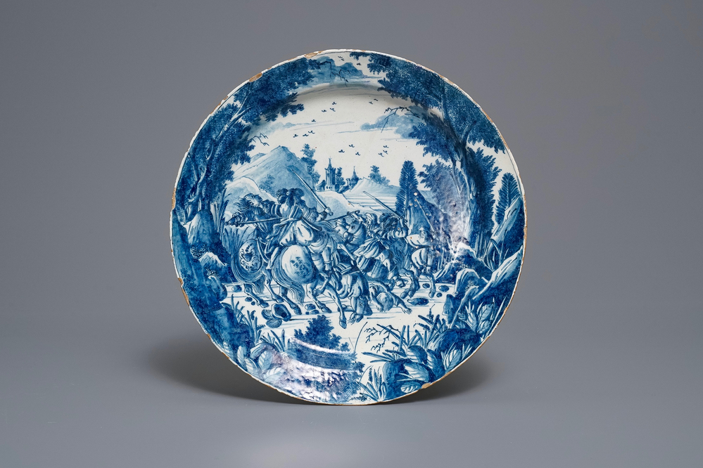 Un plat en fa&iuml;ence de Delft en bleu et blanc &agrave; d&eacute;cor raffin&eacute; d'une bataille de cavaliers, 18&egrave;me